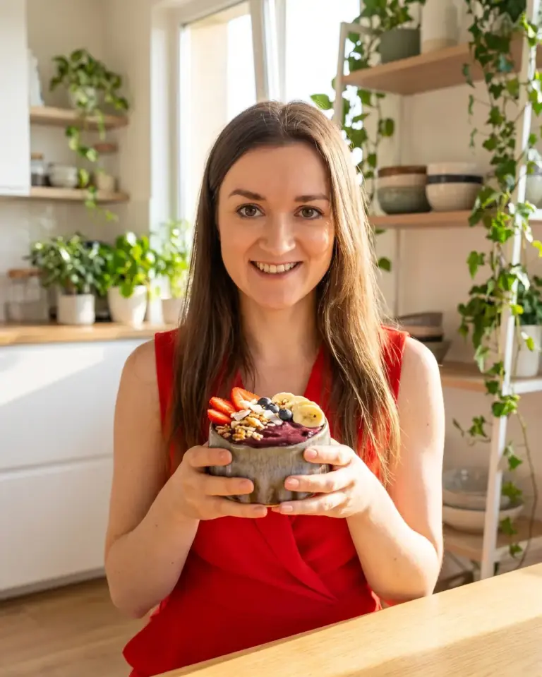 Kobieta w czerwonej sukience trzyma bowl z açaí i owocami w czarce