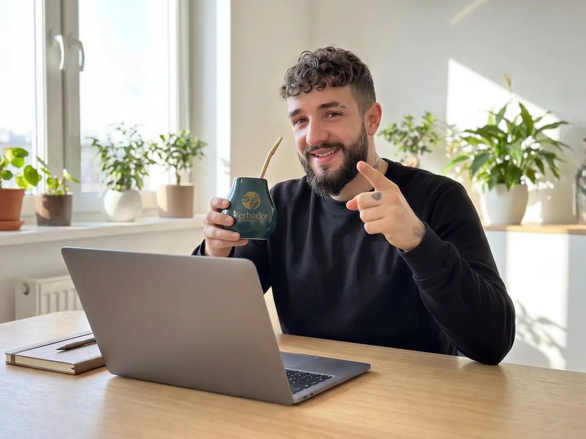 Mężczyzna z brodą przy laptopie w domu trzyma matero Yerbador i wskazuje palcem