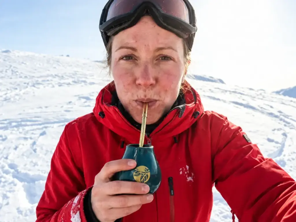 Narciarka pije yerba mate z matero na ośnieżonym stoku