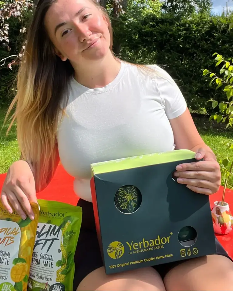 Kobieta na trawie z zestawem prezentowym i opakowaniami yerba mate